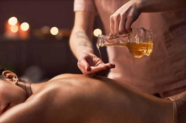 Masseuse pouring almond oil for massage